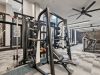 The Main On University offers a modern gym with weight machines, treadmills, and exercise equipment on a carpeted floor, ceiling fans above.